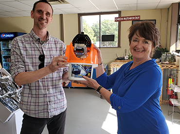 Owner, Allen Sheehan, and a property visitor hold up item in the convenience store